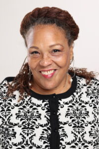 White background; Light-skinned Black women wearing a black and white blazer, smiling.
